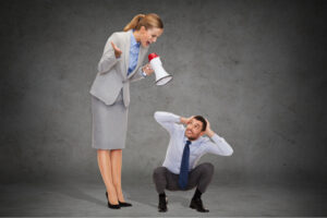 business, communication and office concept - angry businesswoman with megaphone screaming at businessman