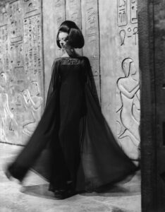 An Italian model with 'Cleopatra' hairstyle wearing a black chiffon fitting dress. Italy, 1962