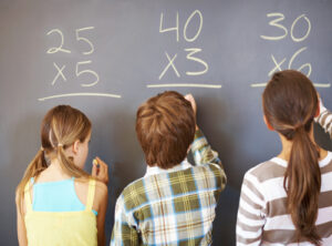 Children writing equation solution on chalkboard