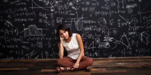 Young girl sits by mathematical chalkboarda